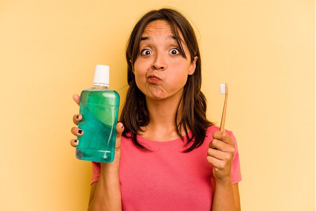 Dental Care Mistakes You Didn’t Know You Were Making 4 A person looking confused while holding a bottle of mouthwash contemplating whether to use it or not