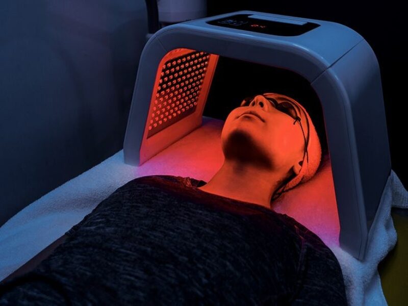 Best 5 Ways to Get Vitamin D Without Excessive Sunlight 4 A woman under a UV lamp with glasses on, in a dark ambient setting