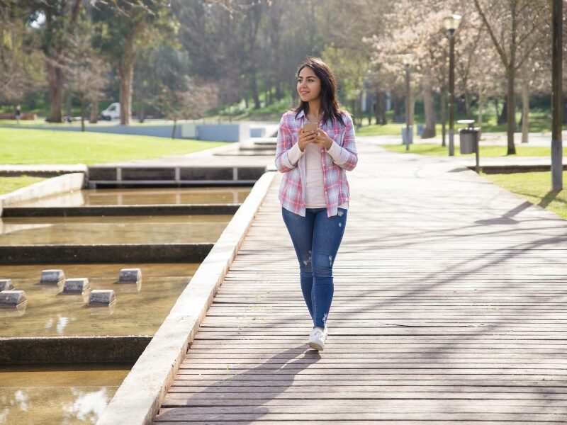Best 5 Ways to Get Vitamin D Without Excessive Sunlight 5 A younge lady walking in a park on a sunny day.