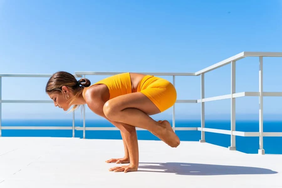 Woman balancing in Bakasana crow pose, an arm-balance yoga posture