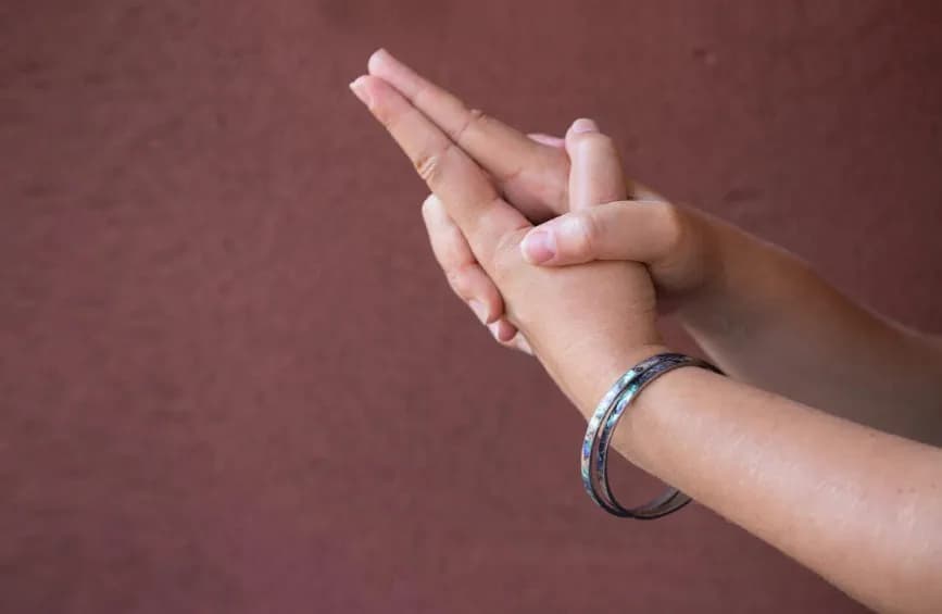 Hands forming Kali Mudra with interlaced fingers and joined index fingers raised like a sword