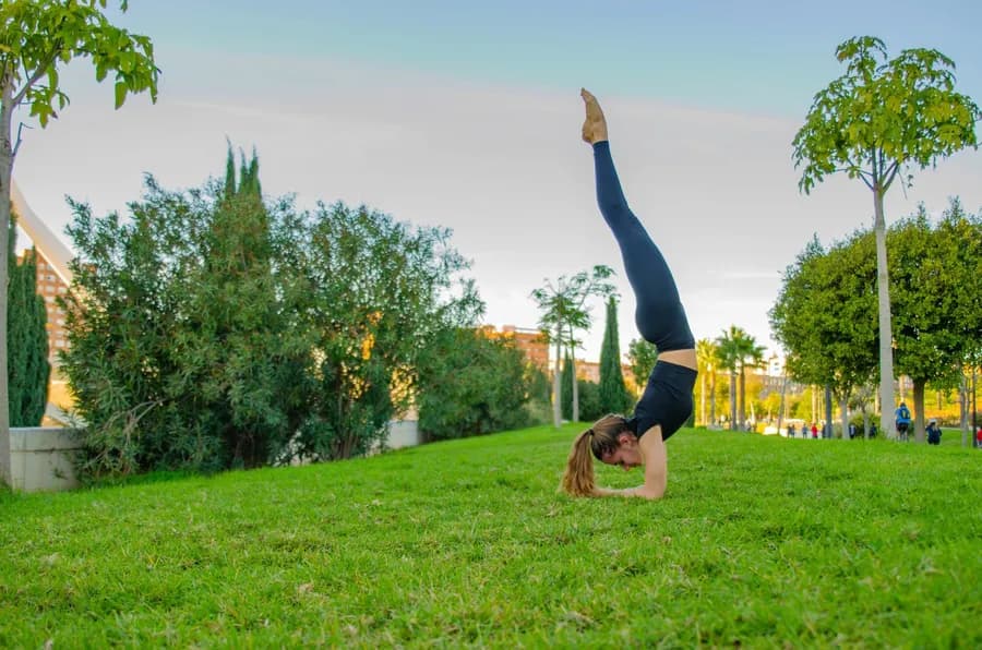 Woman in forearm stand (Pincha Mayurasana) practicing yoga outdoors