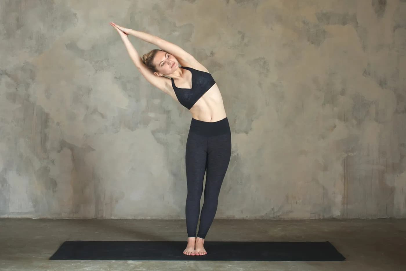 Woman practising Tiryaka Tadasana, the Swaying Palm Tree Pose standing lateral bend