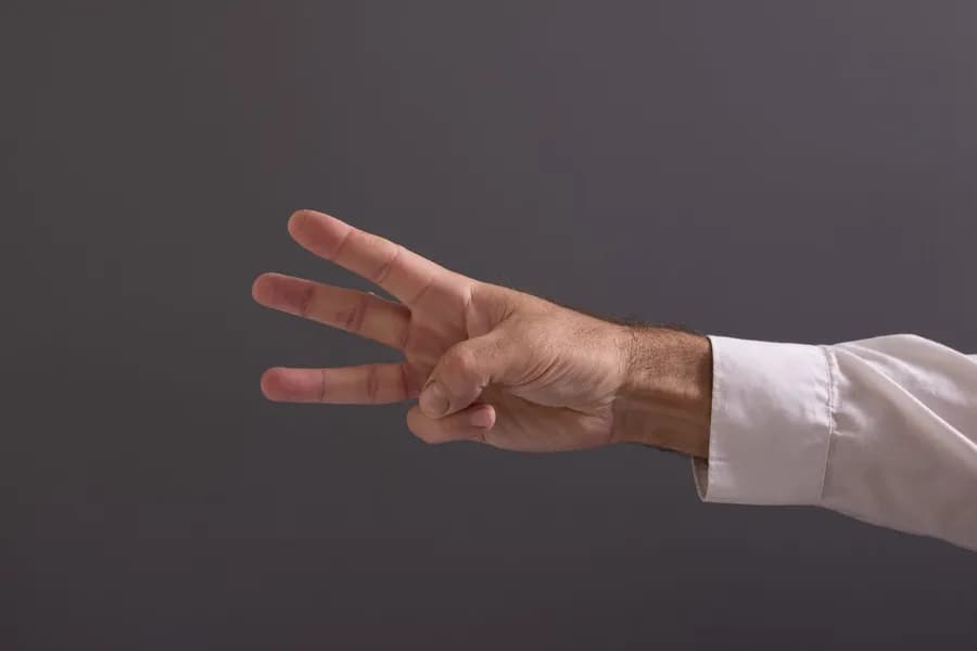 Hands forming a water mudra gesture against a gray background