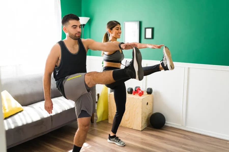 Active couple stretching together at home during an active recovery workout