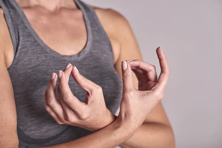 Woman meditating with fingertips together in Apana Mudra hand gesture