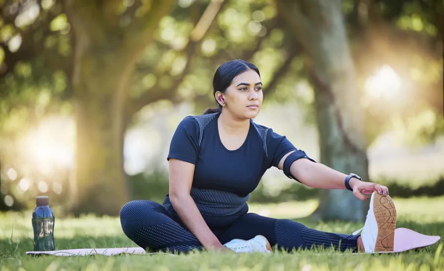 Woman doing a mobility stretching exercise outdoors in a park