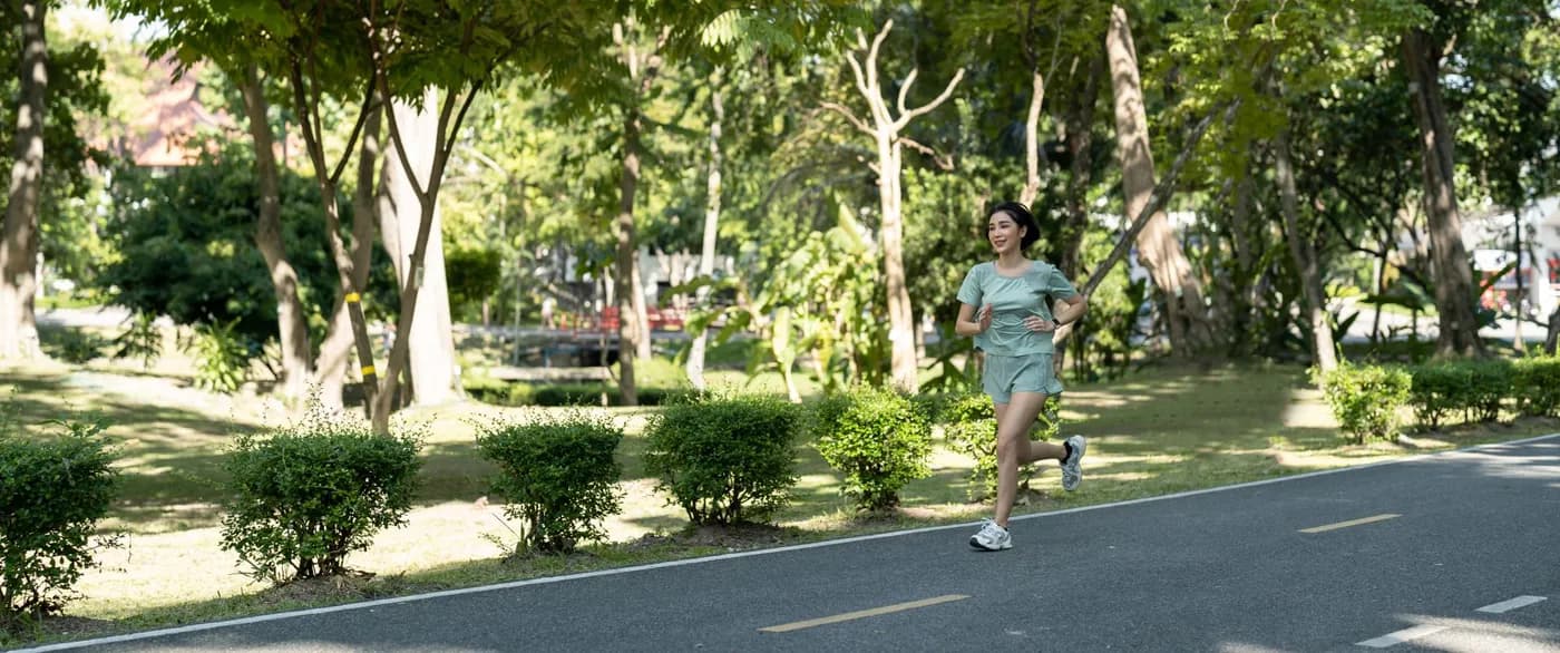 Asian woman running outdoors in a park, illustrating the benefits of running for women