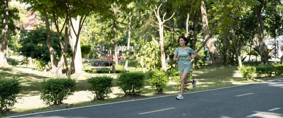 Asian woman running outdoors in a park, illustrating the benefits of running for women