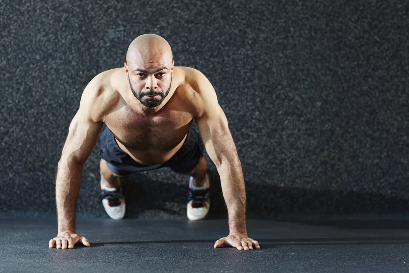 Muscular man doing push-ups as part of a burpee workout for fat loss
