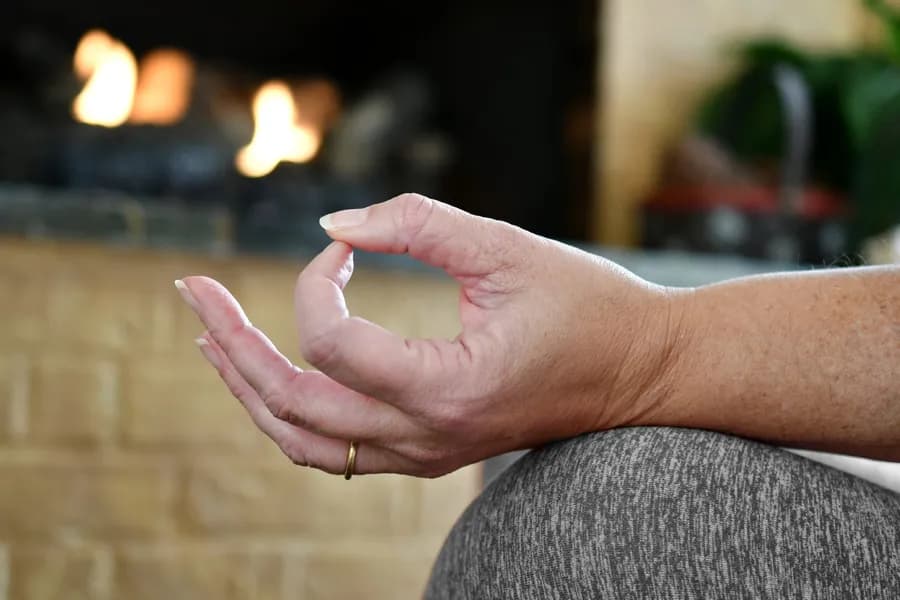 Woman practicing yoga at home focusing on a calm hand mudra gesture
