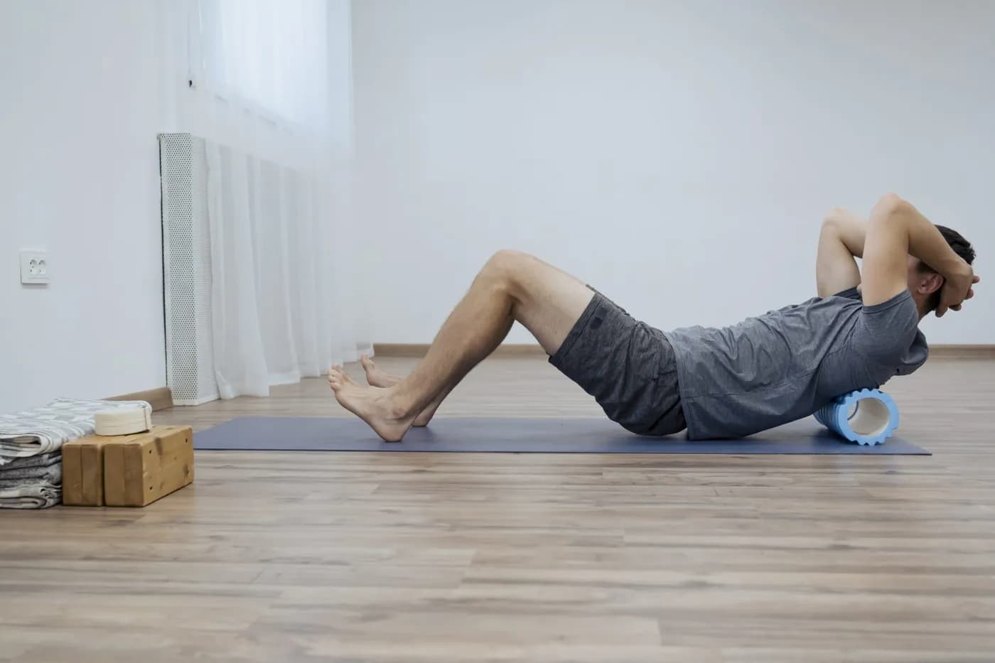 Man stretching his back with a foam roller, representing strength and mobility work relevant to pelvic floor training