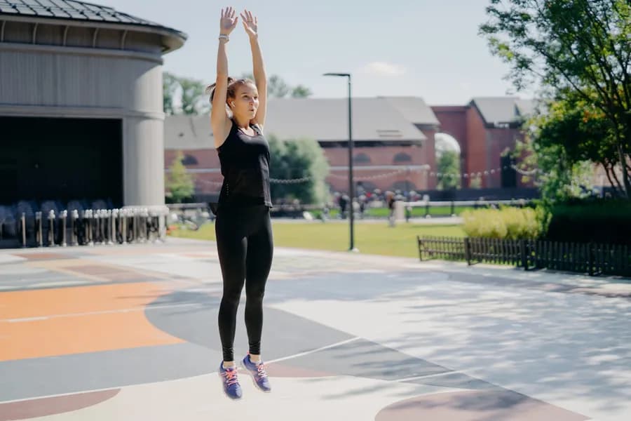 Woman mid-jump performing a jumping jack outdoors