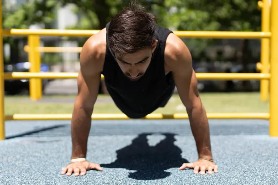 Athletic man doing a push-up outdoors in a park