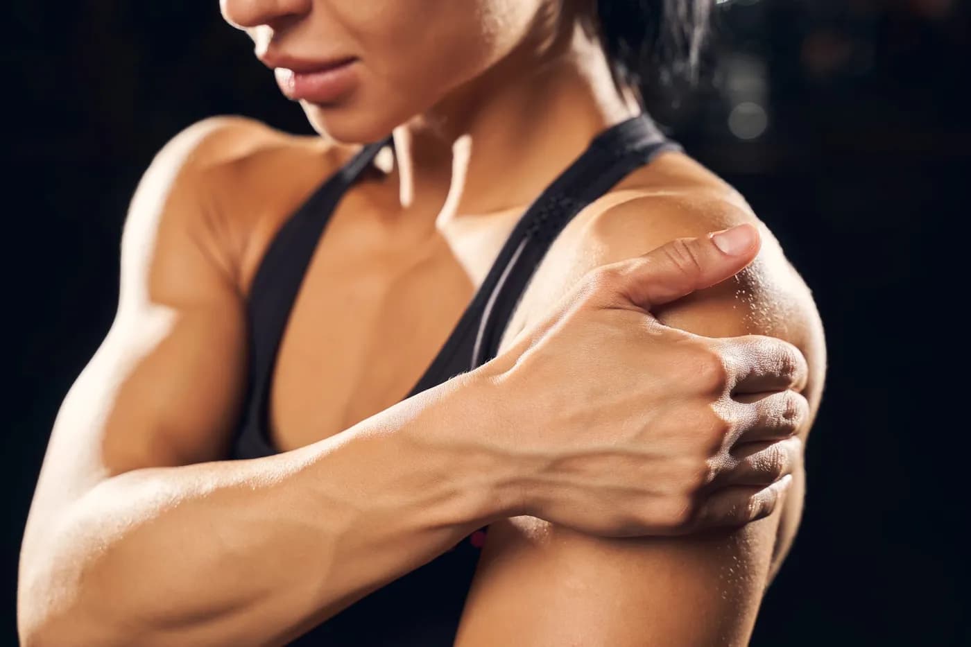 Woman holding her shoulder during a gym workout