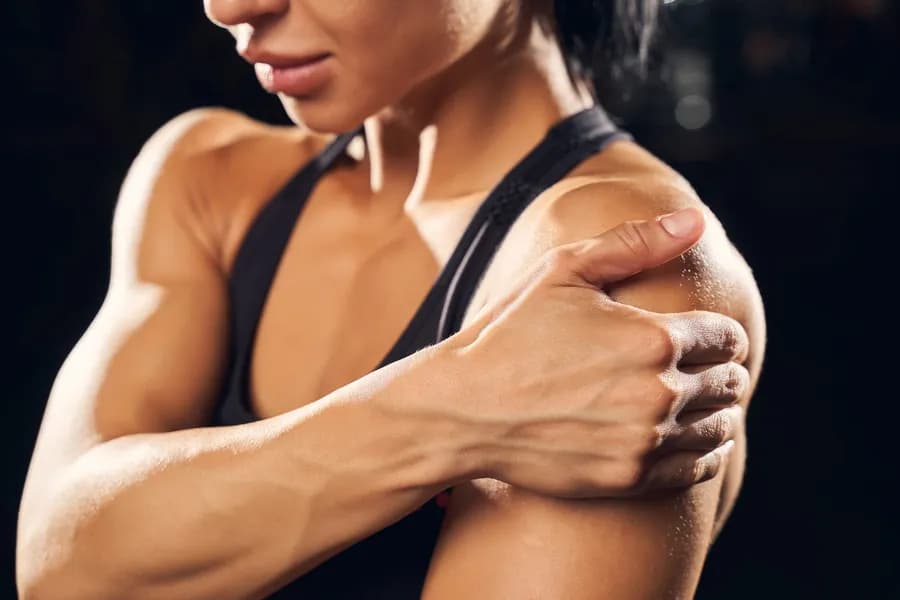 Woman holding her shoulder during a gym workout