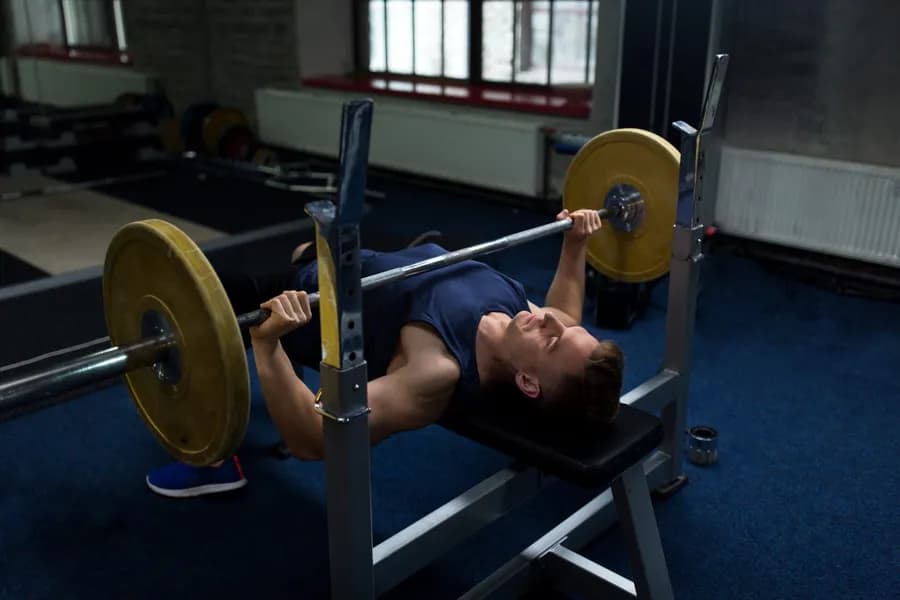 Young man flexing muscles with a barbell in the gym