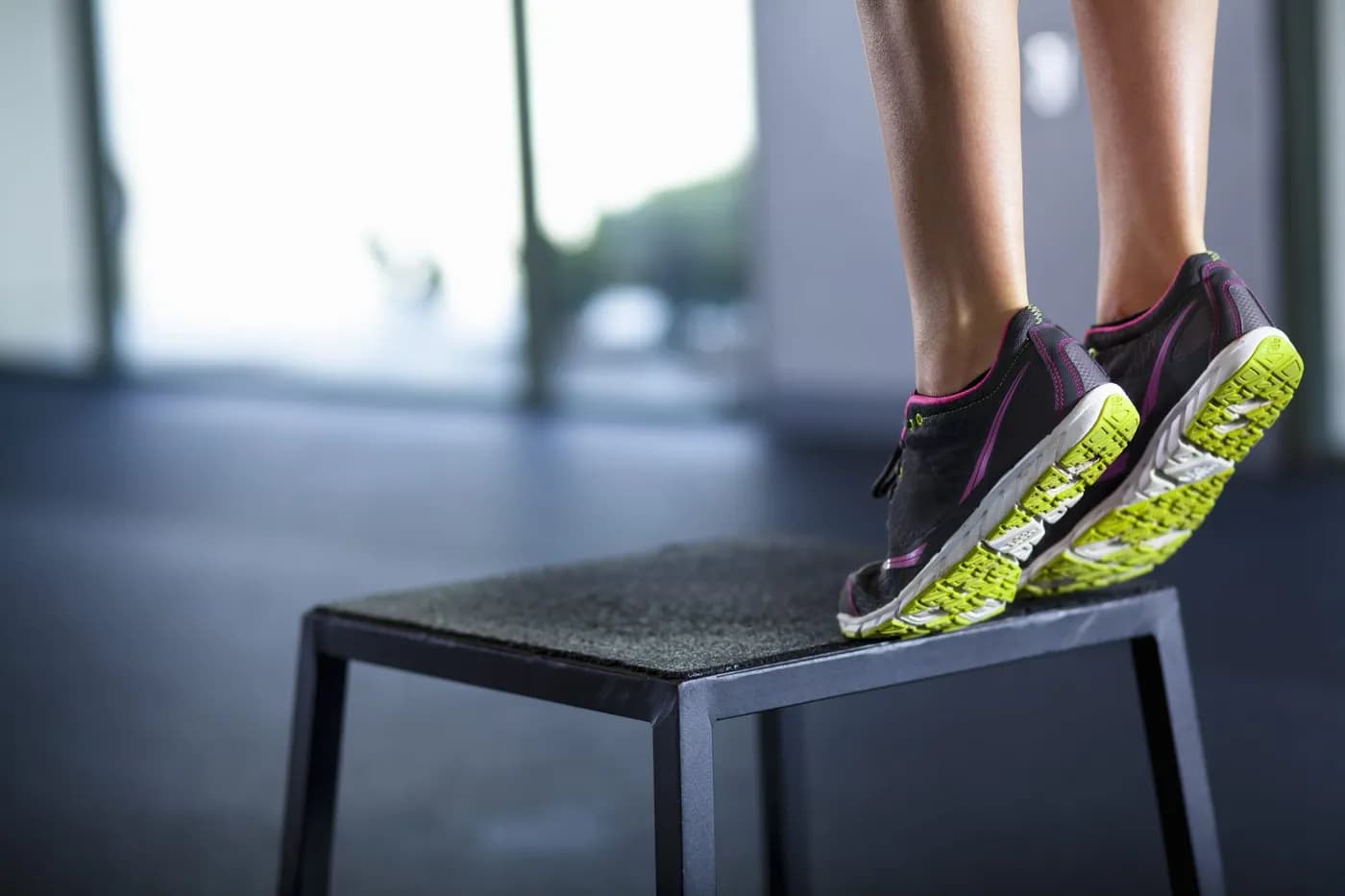Athletic woman stepping onto an exercise box, representing calf raise training