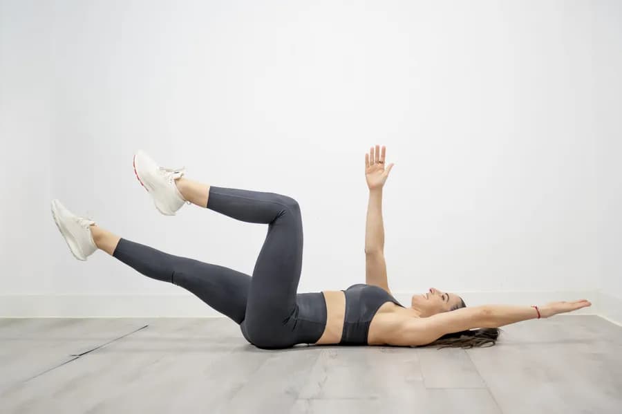 Woman lying on floor demonstrating dead bug core exercise setup