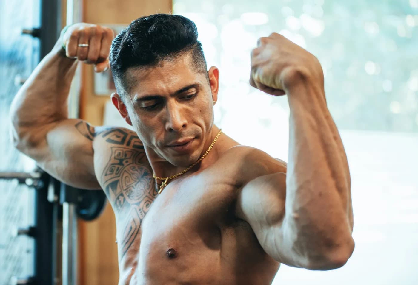 Muscular man flexing his biceps in a gym, representing strength and muscle building