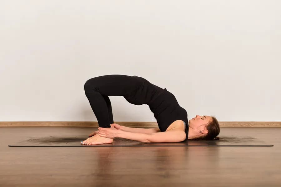 Woman performing a glute strengthening exercise at home to build stronger, firmer glutes