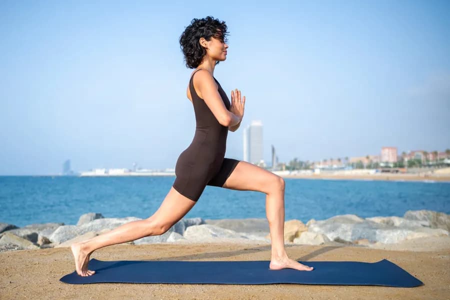Woman practicing a crescent lunge outdoors, building lower-body strength and flexibility