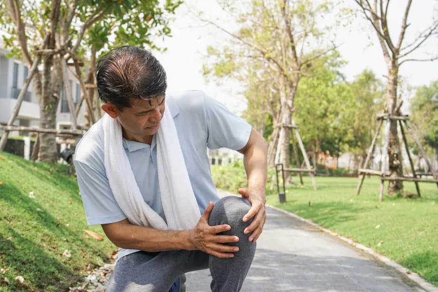 Man holding his knee in pain outdoors, representing joint inflammation