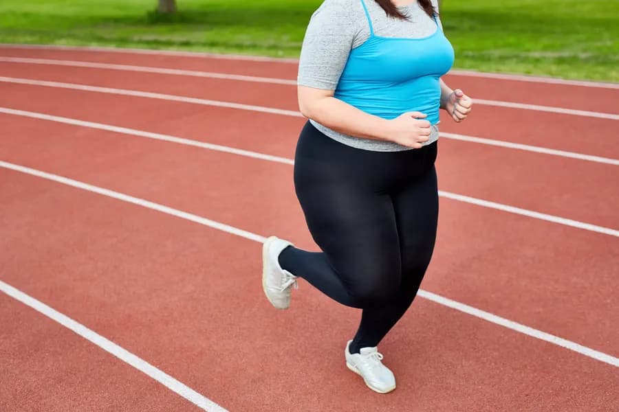 Woman running on an outdoor track during a workout for weight loss