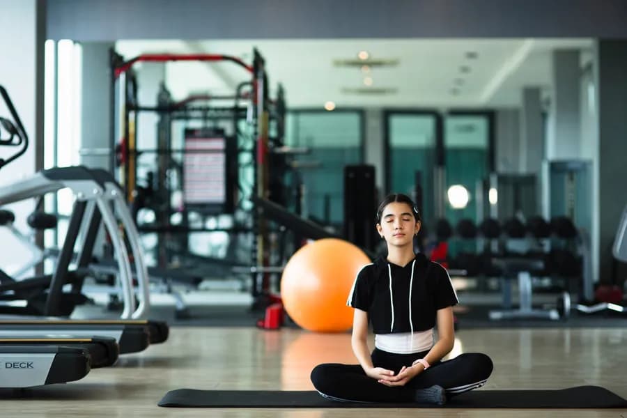 Young girl practising a yoga pose on a mat at home