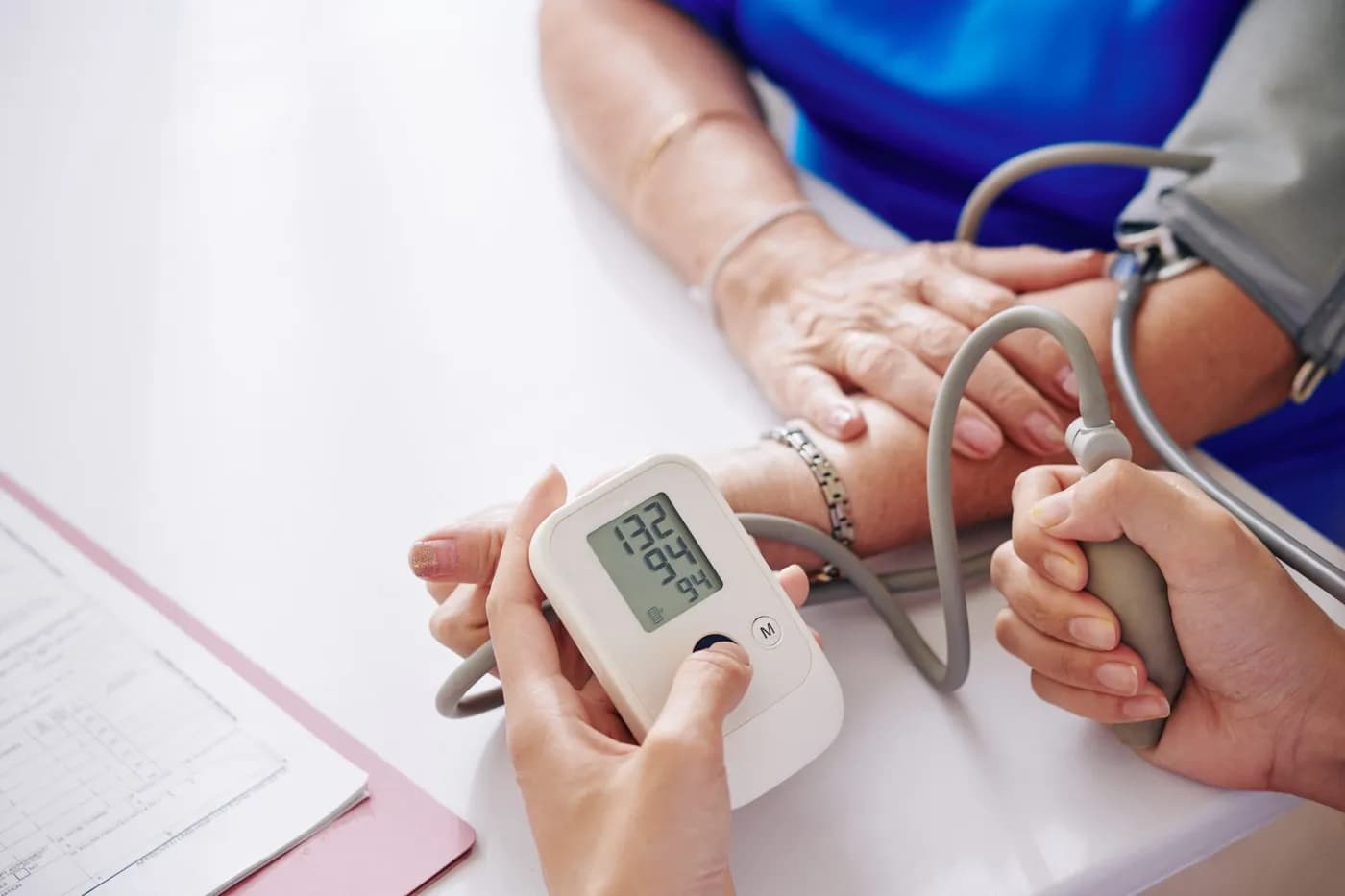 Doctor checking a patient's blood pressure reading in a hospital setting to assess hypertension