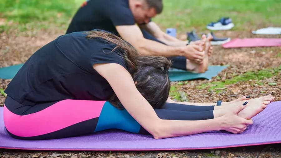 People stretching outdoors in a seated forward fold