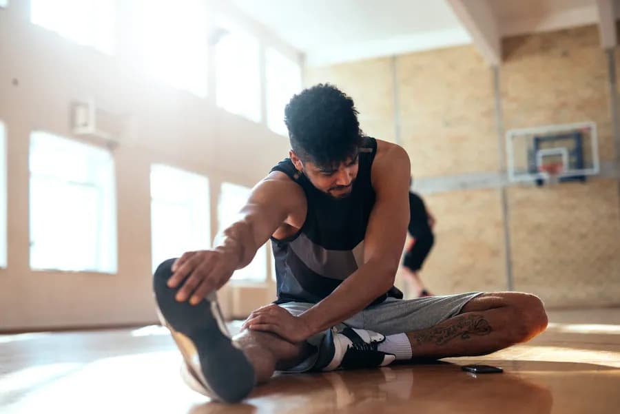 Man warming up with dynamic stretches before a workout on a basketball court