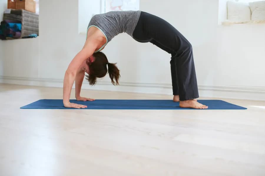 Woman demonstrating the complete backbend arc of Purna Chakrasana (Full Wheel Pose)