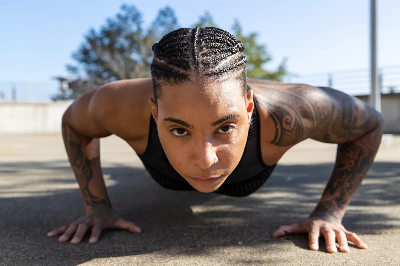 Determined woman doing push-ups outdoors in sunlight