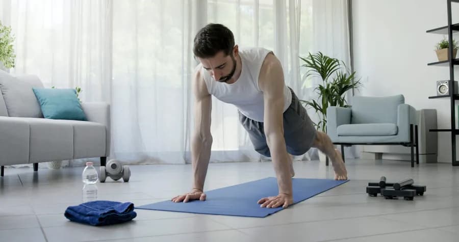 Man doing push-ups on an exercise mat indoors