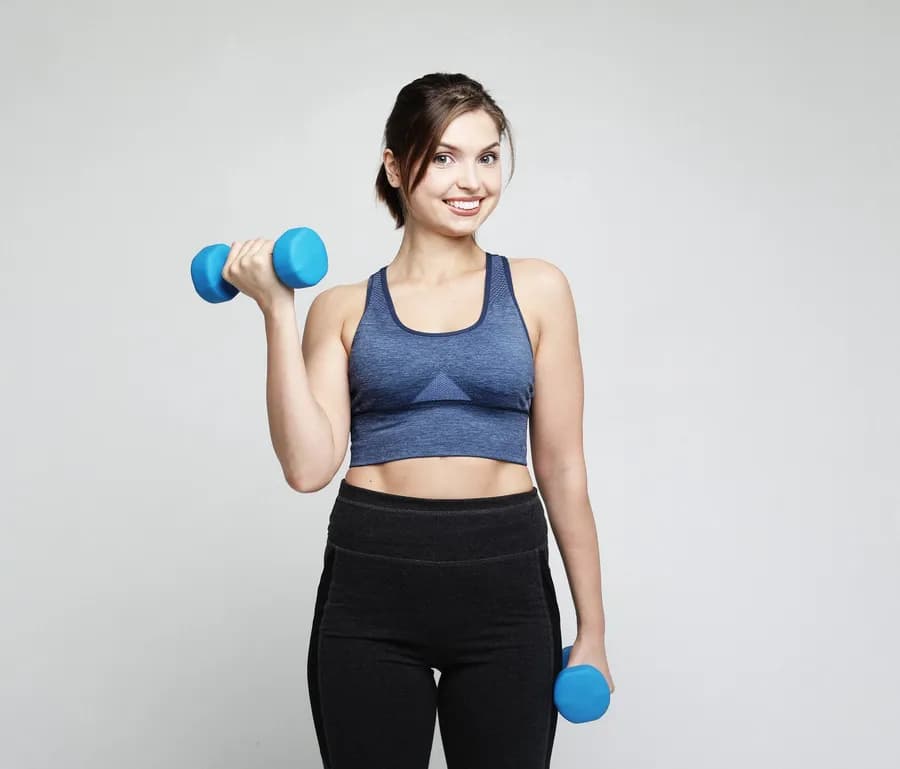 Smiling woman lifting dumbbells during a strength training workout at home