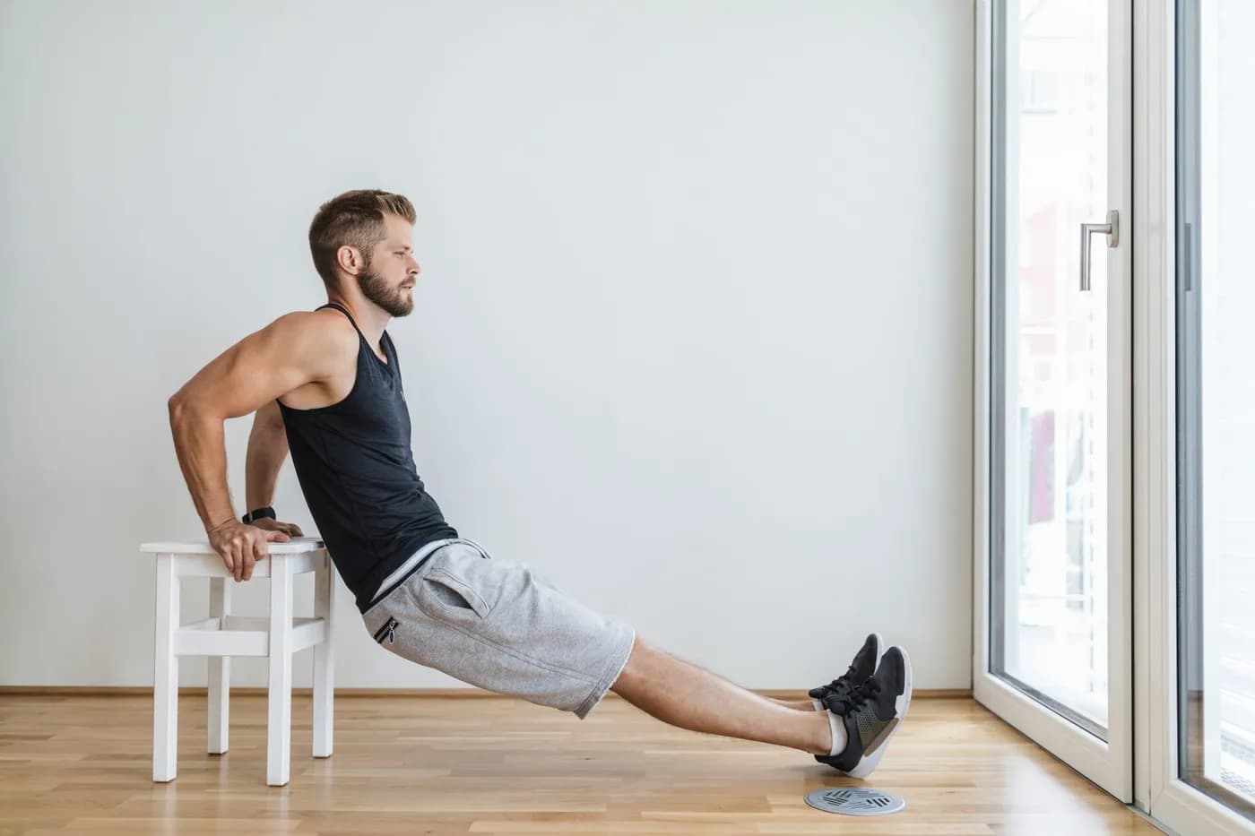 Man exercising at home using a chair for triceps dips