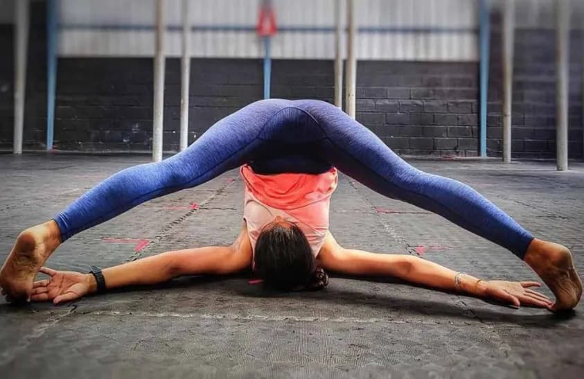 Woman demonstrating the inverted wide-leg stretch of Supta Konasana (Reclined Angle Pose)