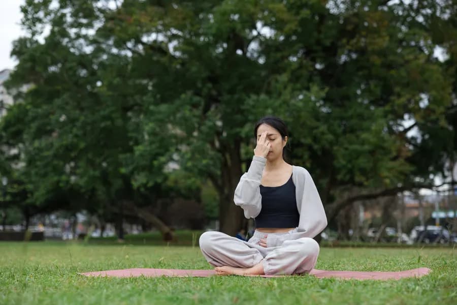 Woman practicing pranayama breathing technique outdoors