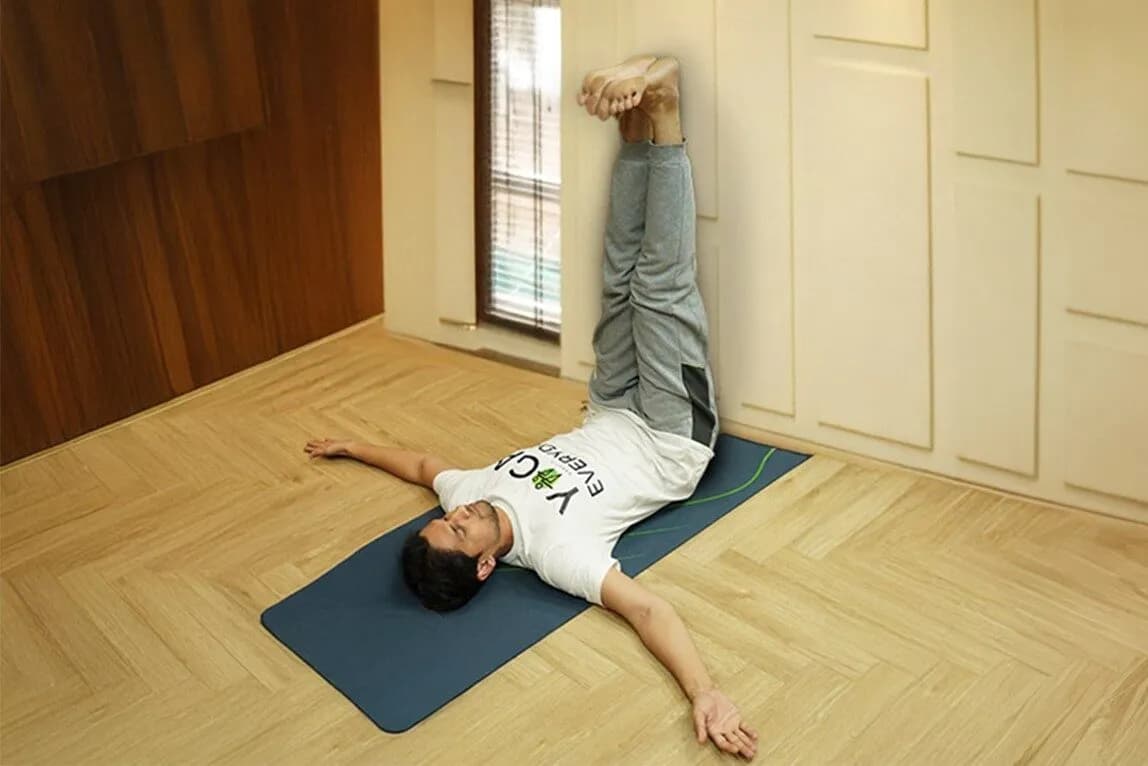 Person practising Viparita Karani Mudra, legs raised up against a wall