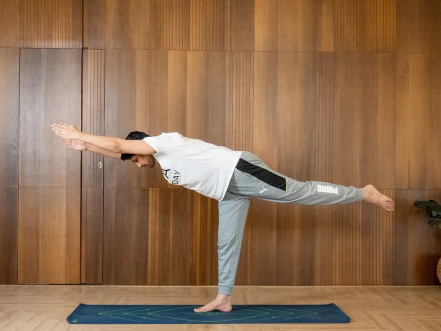 Woman balancing in Virabhadrasana 3 (Warrior III), torso and rear leg extended into a T-shape