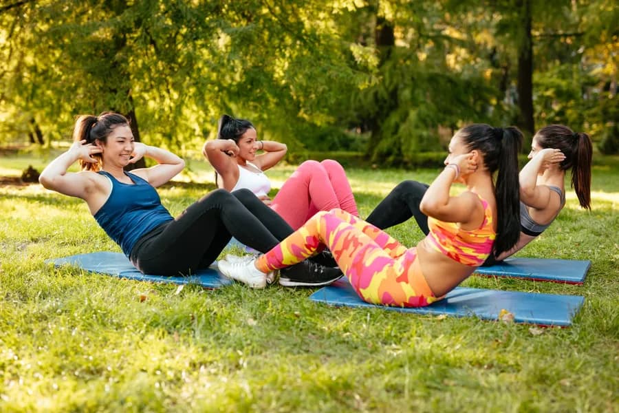 Four women exercising outdoors in a park, training their core strength together