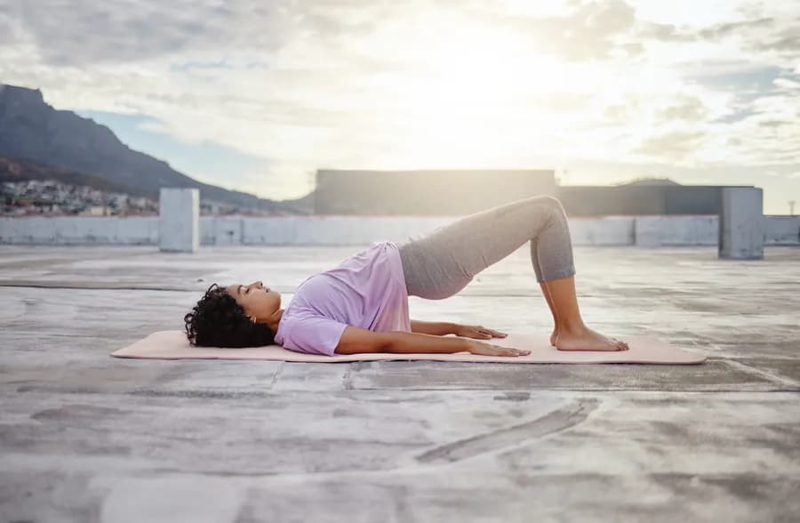 Woman performing a hip thrust exercise outdoors, illustrating pelvic floor engagement for Kegel exercises