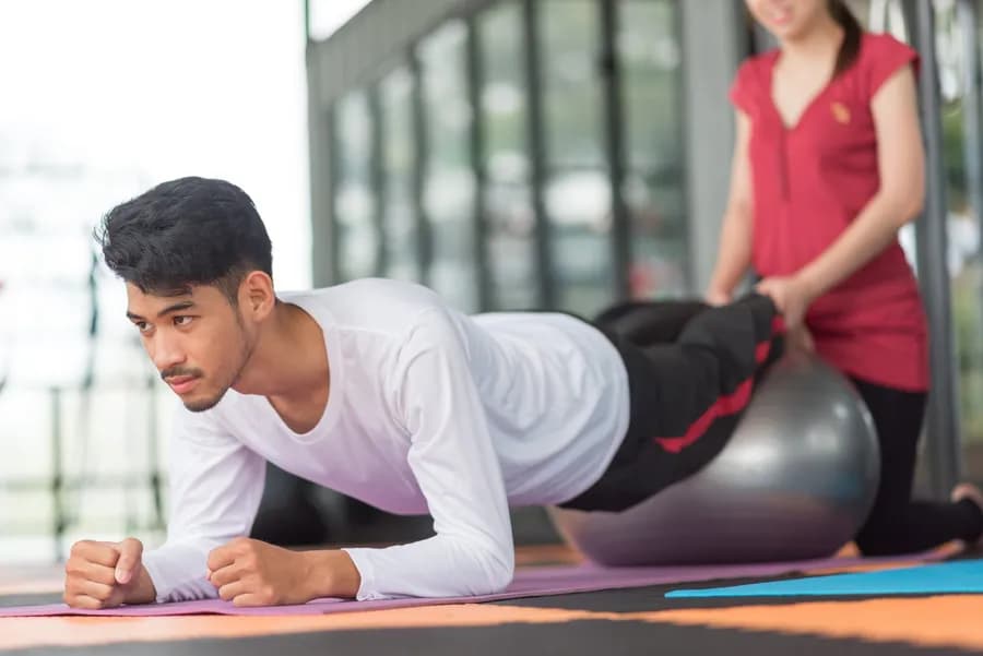 Man and woman exercising together with a stability ball