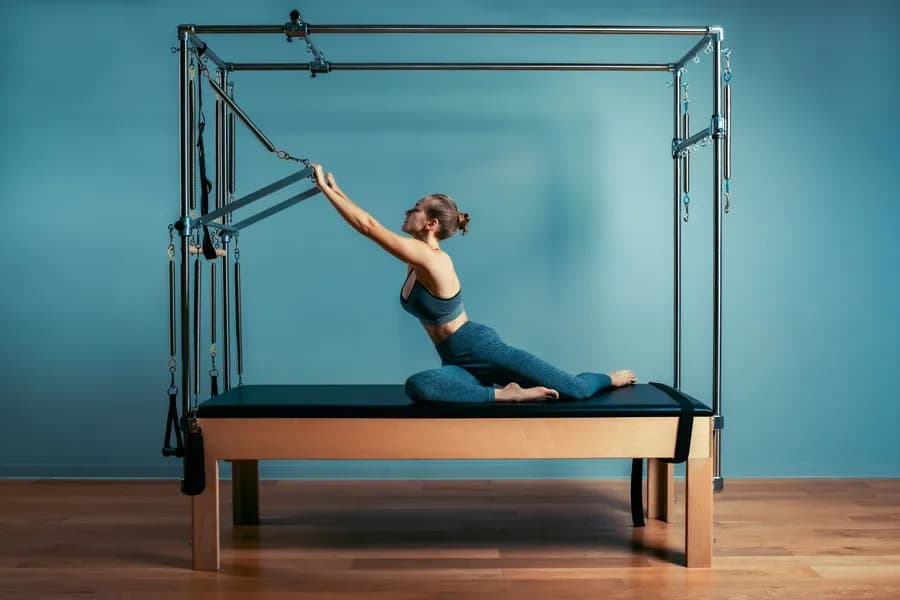 Woman performing pilates exercise on a reformer machine