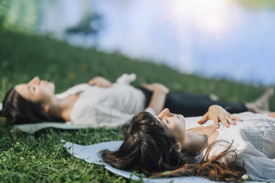 women reclining in a meadow on yoga mats