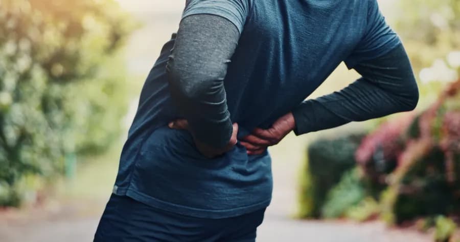 Person holding lower back in pain from sciatica while outdoors
