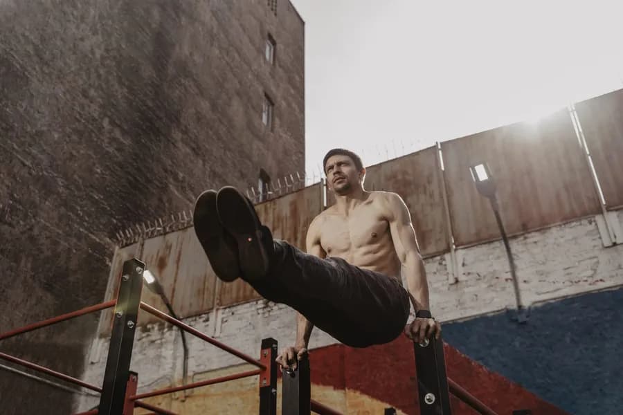 Athletic man doing an L-sit on parallel bars