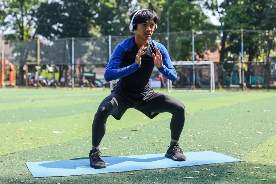 Sporty athlete doing squats during a Tabata-style workout
