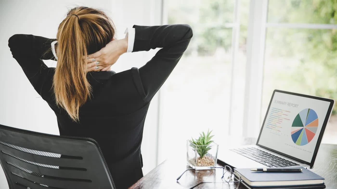Young woman experiencing neck pain while sitting at her desk during work